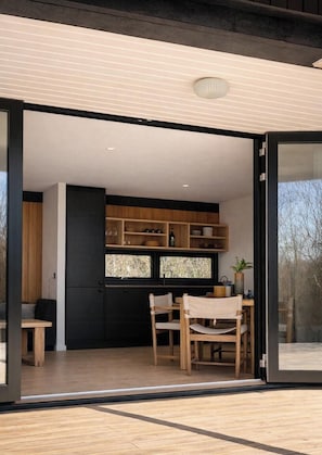 Eine moderne Küche mit Holzausstattung, ein Essbereich mit Tisch und Stühlen sowie ein großes Fenster.