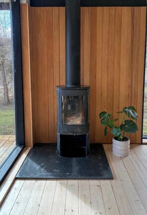 Ein Kaminofen in einem Raum mit Holzwänden und einem Blumentopf.