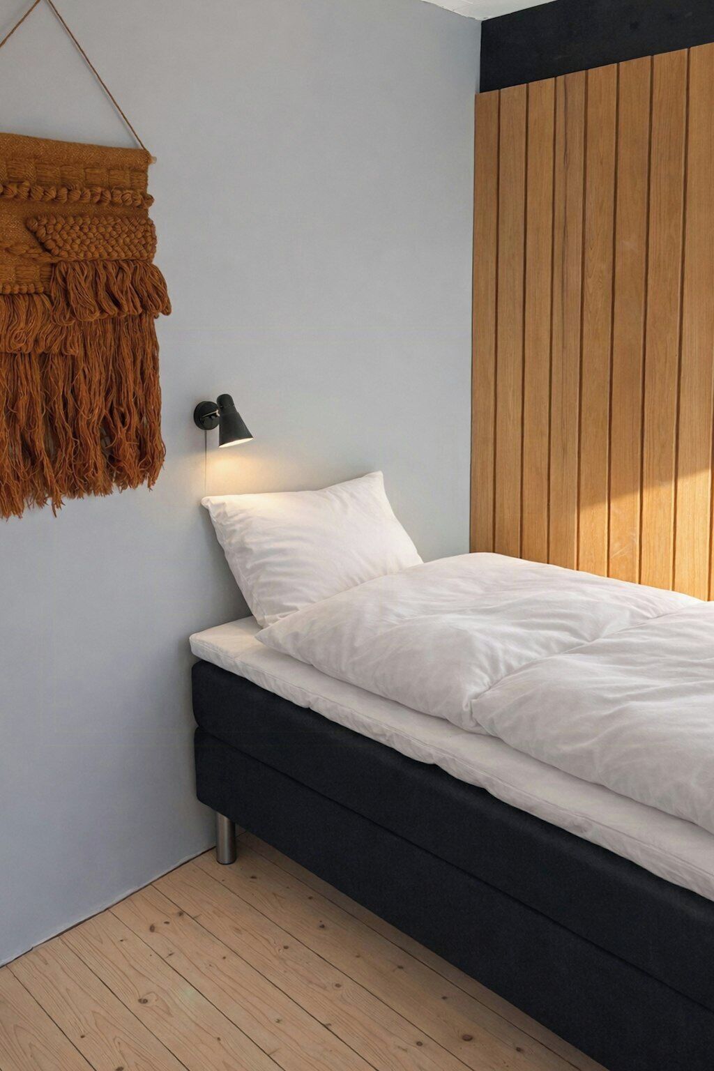 Una camera da letto con un letto, una lampada a parete e un pannello di legno al muro.