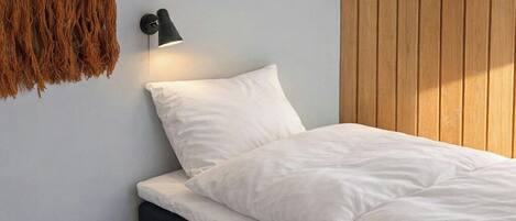 Una camera da letto con un letto, una lampada a parete e un pannello di legno al muro.
