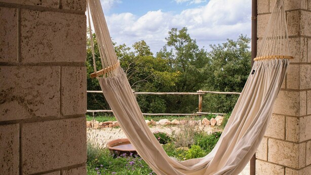 A hammock in a stone-walled outdoor area with a view of greenery and a clear sky. - Panoramic refuge on Monte Pelato (Gualdo Cattaneo)
