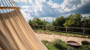 A hammock in a garden with a wooden fence, a gravel path, and a pond. - Panoramic refuge on Monte Pelato (Gualdo Cattaneo)