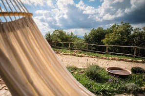 Eine Hängematte in einem Garten mit Holzzaun, Kiesweg und Teich.