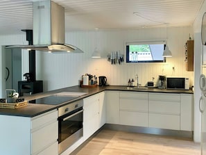 Eine moderne Küche mit weißen Schränken, einem Backofen, einem Herd, einer Mikrowelle und einem Fenster über der Spüle.