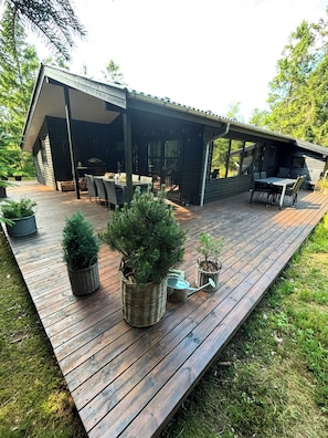 Eine Holzterrasse mit Gartenmöbeln, Blumentöpfen und einem überdachten Patio.