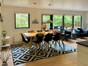 Ein moderner Essbereich mit einem weißen Tisch, einem schwarz-weißen Teppich und schwarzen Stühlen.