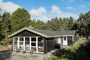 A cabin with a large glass windowed porch, a chimney, and a small attached shed. - Magical atmosphere close to the sea (Sæby)