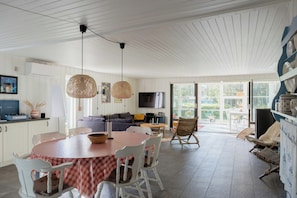 A spacious living area with a dining table, chairs, a sofa, and a television. - Magical atmosphere close to the sea (Sæby)