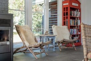 A room with two wicker chairs, a small round table, a fireplace, and a red bookshelf with books. - Magical atmosphere close to the sea (Sæby)