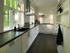 Eine moderne Küche mit schwarzem Arbeitsplatz, weißen Schränken, einer Edelstahlspüle und einem Fenster mit Blick auf Grünflächen.