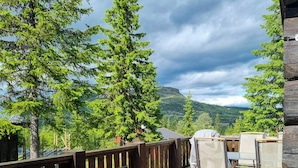 A wooden deck with outdoor seating, surrounded by trees and a mountainous backdrop. - Log cabin directly by the ski slopes (Gausdal)