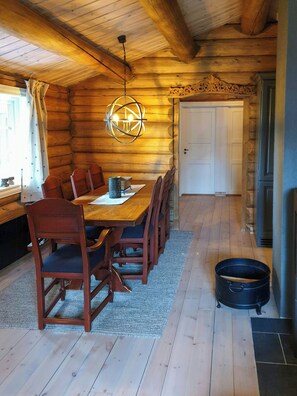 Ein Holzinterieur mit Esstisch, Stühlen, einer Chandelier und einem Kamin.