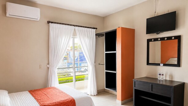 Quarto de hotel com duas camas, um guarda-roupa, uma mesa de toucador com espelho e um ar condicionado.