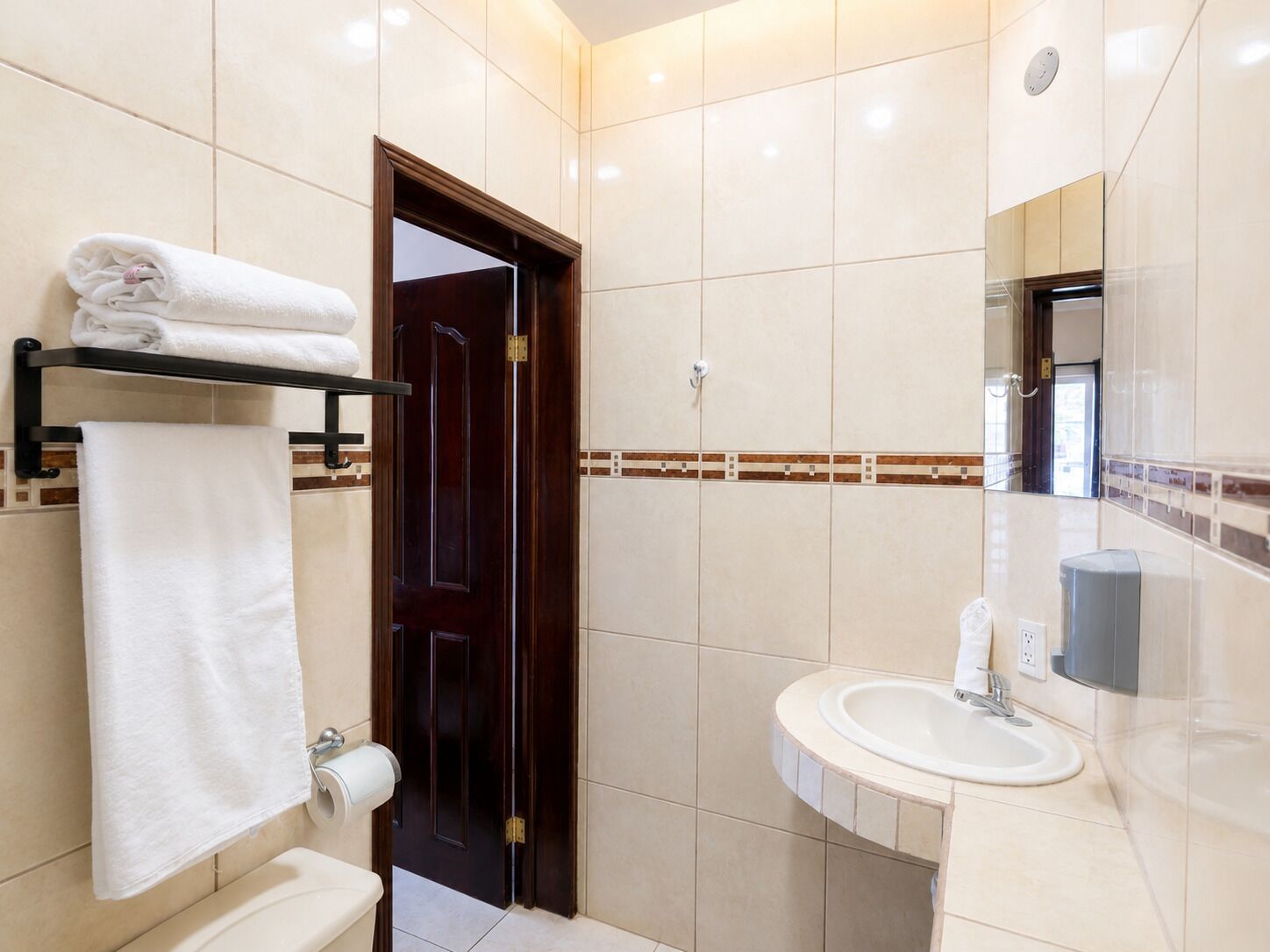A bathroom with a toilet, sink, towel rack, and a mirror.