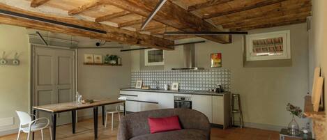 A kitchen with a dining table, a sofa, and a small table with a vase.