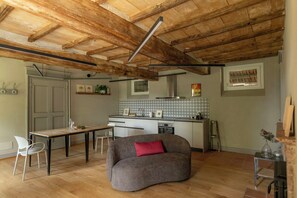 A kitchen with a dining table, a sofa, and a small table with a vase. - Farmhouse among hazelnut groves in the Langhe (Cherasco)