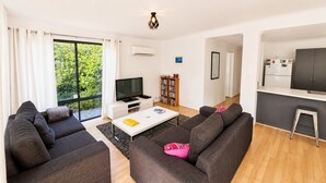 A modern living room with a flat-screen TV, dark sofas, a coffee table, and a bookshelf. - Busso Escape – The Perfect South West Getaway (Broadwater)