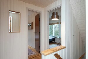 A narrow hallway with wooden walls, a mirror, a hanging light fixture, and a window with a view of trees. - 1960s family home near St Sjørup Beach (Ørsted)