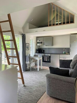 Ein modernes Loft-Apartment mit Küche, Essbereich und Schlafgalerie mit großem Fenster.