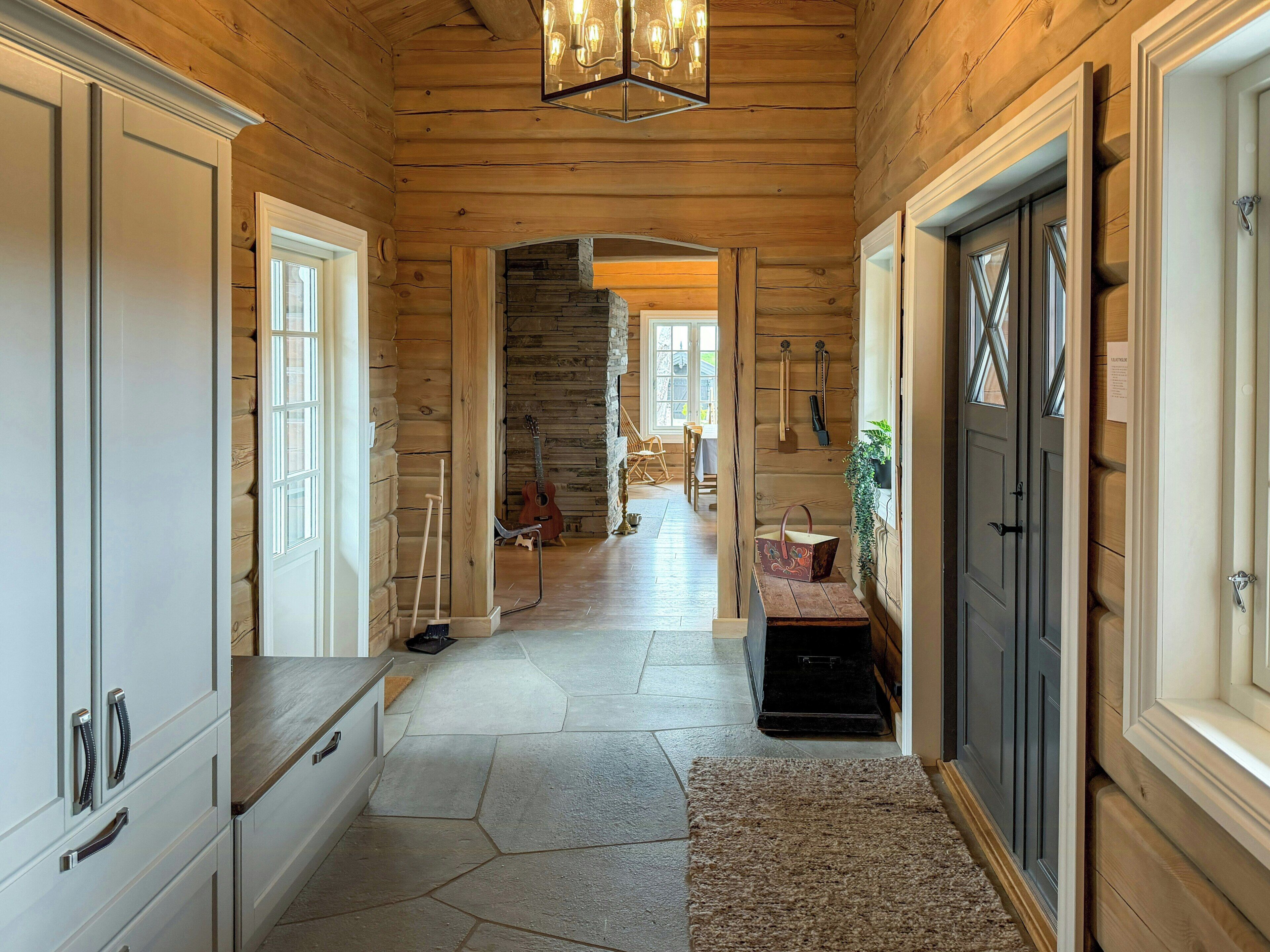 A wooden interior with a stone floor, a staircase, and a bench.