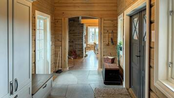 A wooden interior with a stone floor, a staircase, and a bench.