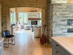 A spacious living area with a fireplace, wooden flooring, and a guitar leaning against the wall. - Timber cabin with hot tub and ski runs in Veggli (Veggli)