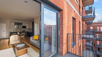 A modern apartment with a kitchen, dining area, and a balcony with a view of the city.