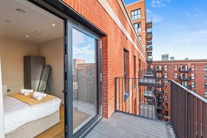 Una moderna camera d'hotel con balcone, un letto e vista sulla città.