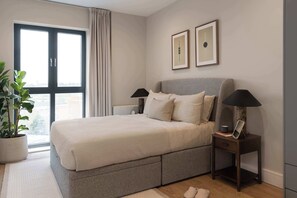 A bedroom with a bed, bedside tables, a window, a plant, and framed pictures on the wall. - Spacious Family Stay in Southside | StayCozy (Birmingham)