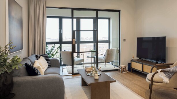 A modern living room with a sofa, armchairs, a coffee table, a TV, and a large window with a city view. - Spacious 3BR Near Bullring | StayCozy (Birmingham)