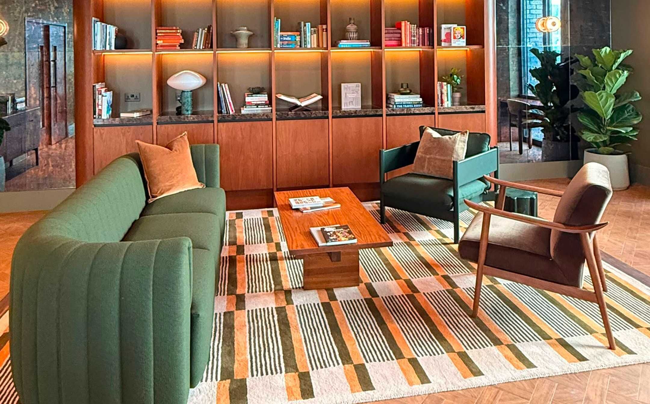 Ein modernes Wohnzimmer mit einer Couch, Sesseln, einem Couchtisch und einem Bücherregal.