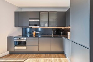 A modern kitchen with a built-in oven, a sink, and a stove. - Spacious 3BR Near Bullring | StayCozy (Birmingham)
