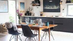A modern kitchen with a dining area, featuring a wooden table, black chairs, and a black pendant light. - Modern flat in Kabelvåg, Lofoten (Nordland)