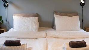 A neatly made bed with two pillows, two bedside lamps, and two towels. - Modern flat in Kabelvåg, Lofoten (Nordland)
