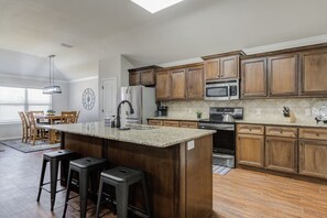 A kitchen with wooden cabinets, a granite countertop, a stainless steel oven, and a built-in microwave. - Bogey`s House - 3BR/2BA Brand New Listing (Lubbock)