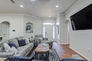 A living room with a sofa, armchairs, a coffee table, and a TV mounted on the wall. - Bogey`s House - 3BR/2BA Brand New Listing (Lubbock)