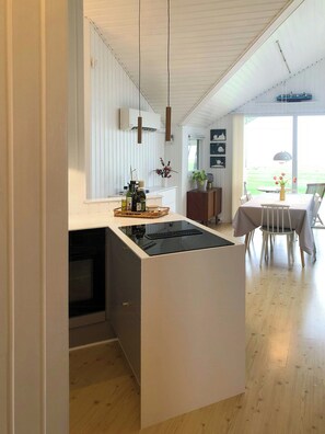 A modern kitchen with a central island, a dining area with a table and chairs, and a view of the outdoors. - Nordals home with panoramic views of Lillebaelt (Nordborg)