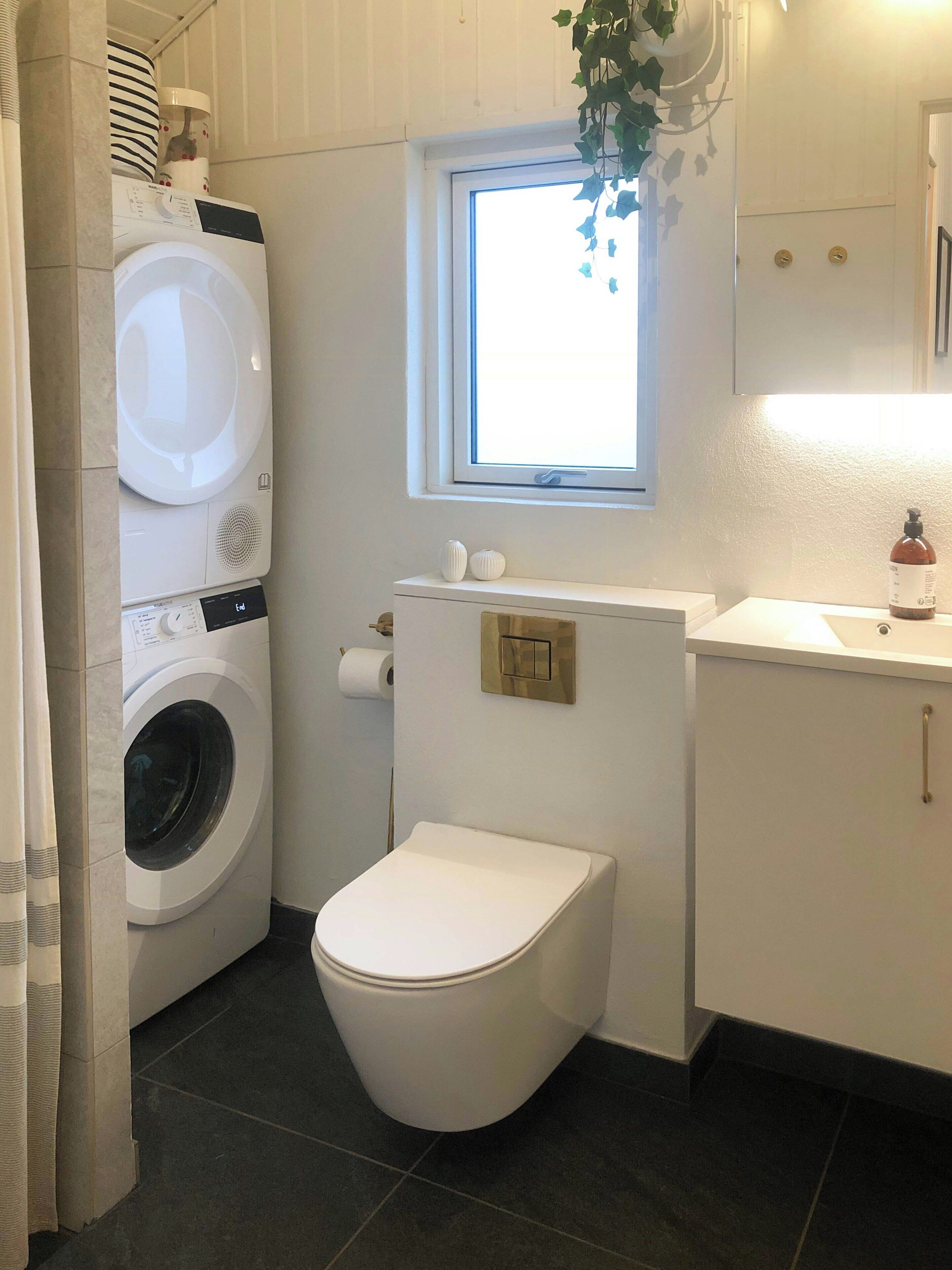 Un baño pequeño con lavadora, inodoro y una ventana.