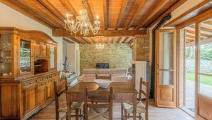 Una mesa de comedor de madera con sillas, una araña, una chimenea de piedra y una pared de piedra.