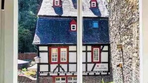 Ein Fenster mit Blick auf ein traditionelles Gebäude mit mehreren Giebeln und einer Steinmauer.
