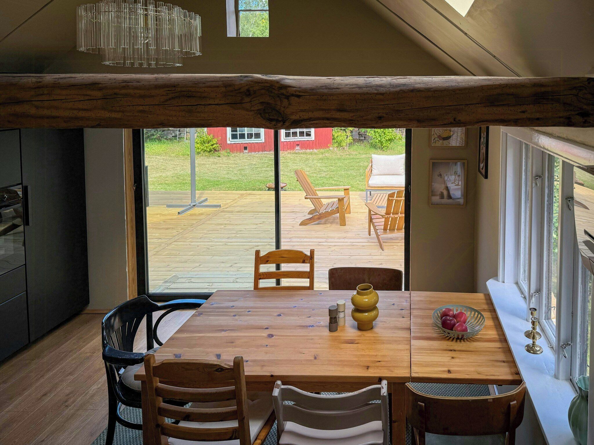 Een eetgedeelte met een houten tafel, stoelen en uitzicht op buiten.