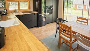 A modern kitchen with wooden countertops, a built-in oven, and a dining area with a table and chairs. - Design house with garden in the heart of Småland (Gullabo)