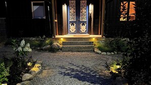 A house with a gravel driveway, a wooden porch, and a decorative door. - Design house with garden in the heart of Småland (Gullabo)
