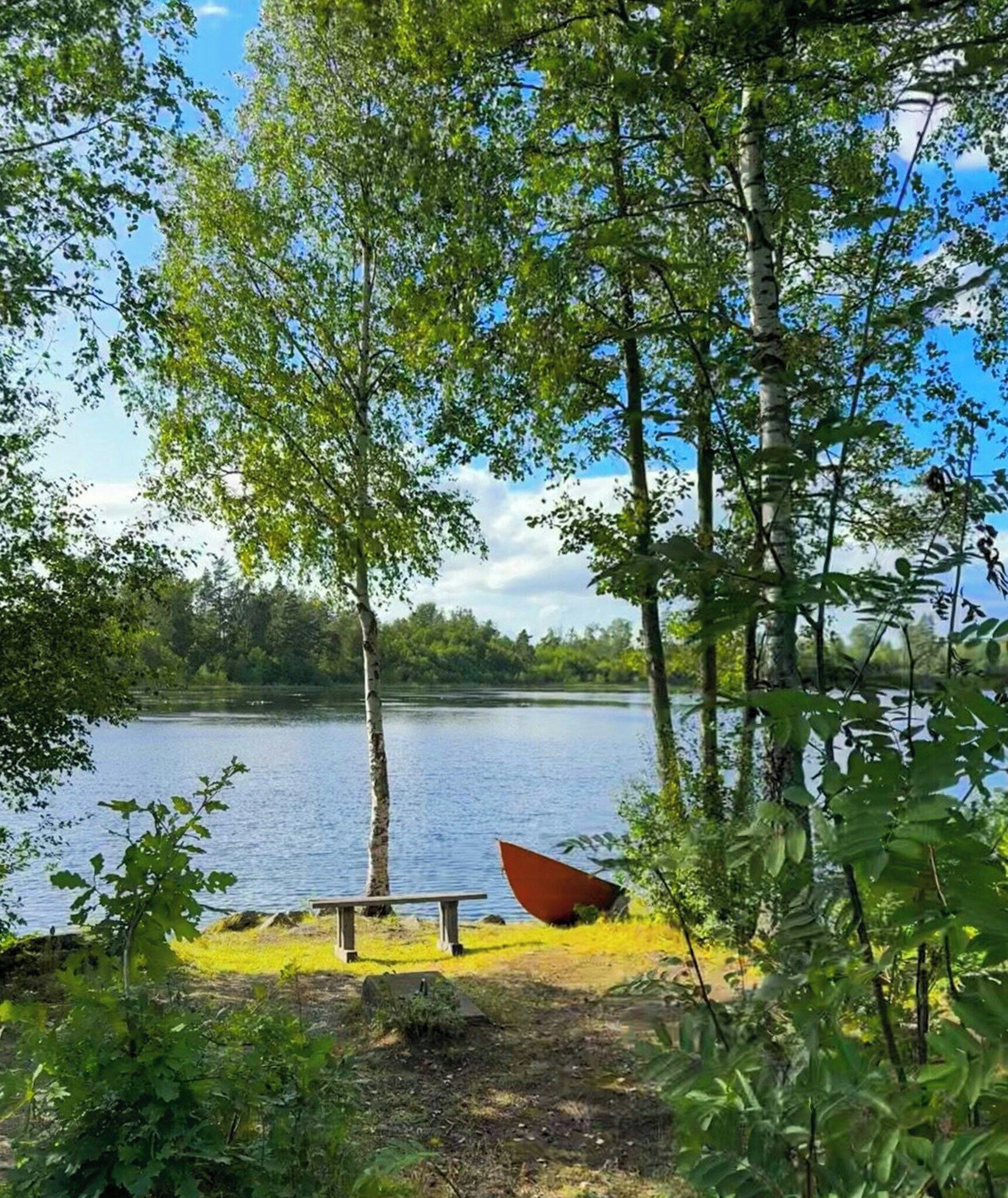En utsikt över sjön med en bänk och en båt.