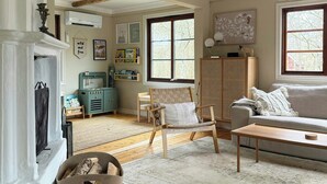 A living room with wooden beams, a fireplace, a sofa, a coffee table, and a window with a view. - Design house with garden in the heart of Småland (Gullabo)