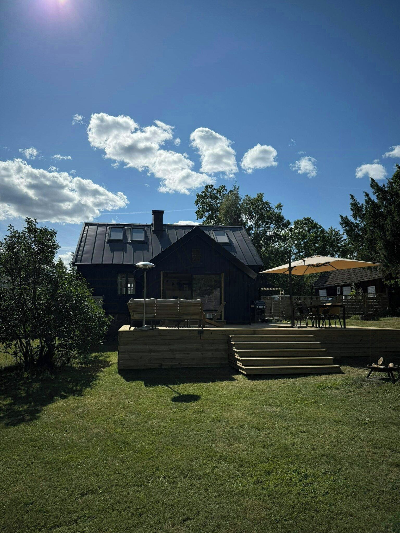 A house with a sloped roof, a visible chimney, and a deck with outdoor furniture.