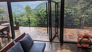 Een moderne kamer met een grote glazen deur die uitkomt op een balkon met uitzicht op de bergen.