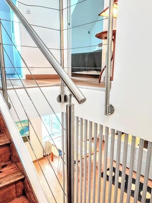 Eine moderne Treppe mit Metallgeländern, Holzstufen und einer Glastrennwand.