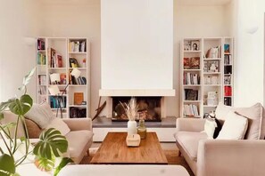Ein Wohnzimmer mit Kamin, zwei Sofas, einem Couchtisch und Bücherregalen voller Bücher.