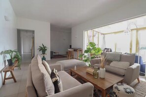 Ein modernes Wohnzimmer mit einer Sofagarnitur, einem Couchtisch und Topfpflanzen.